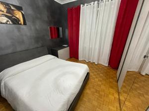 a bedroom with a white bed and red curtains at Casa di Dome in Turin