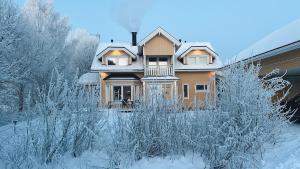 a house covered in snow with trees in front of it at Winter Wonderland Home in Rovaniemi
