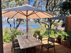 a wooden table with an umbrella on a deck at Capri House in Clareville