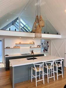 a kitchen with a large island with bar stools at Capri House in Clareville +3 photos