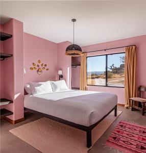 a pink bedroom with a large bed and a window at Salt Pool - Sauna - Cold Plunge - Lux Desert Ranch in Pioneertown +93 photos