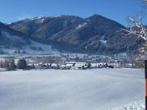 Un gran campo cubierto de nieve con una ciudad y montañas. en Gemütliche Ferienwohnung In Unterammergau, en Unterammergau 3 fotos más