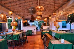 a restaurant with green tables and chairs and chandeliers at Palma Serena Finca Hotel in Santa Fe de Antioquia
