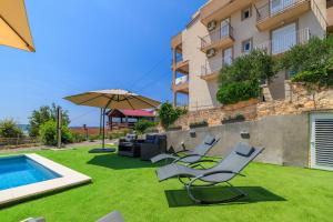a yard with chairs and an umbrella and a swimming pool at Apartments San in Dramalj