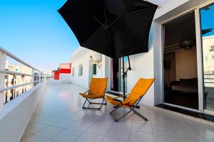 two chairs and an umbrella on a balcony at L'Andalou -3 bedrooms with Parking in Downtown in Kenitra