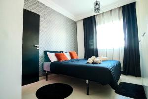 a bedroom with a blue bed with orange pillows and a window at L'Andalou -3 bedrooms with Parking in Downtown in Kenitra