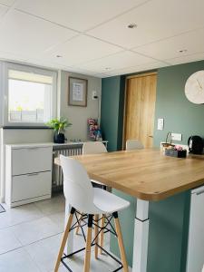 a kitchen with a wooden table and white chairs at Élégant 2 pièces au calme, axe Metz-Luxembourg in La Celle-sous-Gouzon