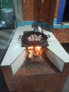 a grill with a pan of food and a kettle on it at Sitio Daniela in São João Batista