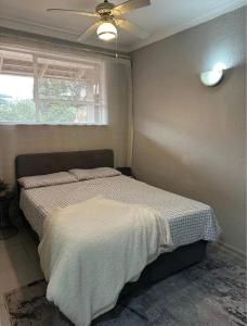 a bedroom with a bed and a ceiling fan at Welcome Home in Cape Town
