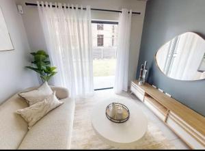 a living room with a white couch and a mirror at Welcome Home in Cape Town