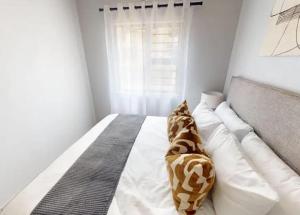 a white bedroom with a bed with brown and white pillows at Welcome Home in Cape Town