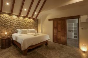 Un dormitorio con una cama y una pared de piedra. en Baan Chang Sanctuary, en Laguna Phuket