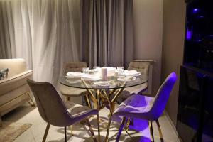 une salle à manger avec une table en verre et des chaises violettes dans l'établissement Appartement calme et luxueux, à Hydra