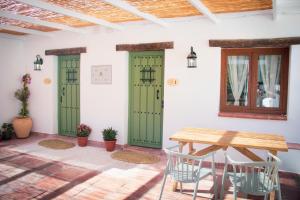 a room with green doors and a table and chairs at El Charcon Alojamiento Rural in El Chorro