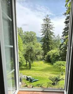 a window with a view of a field of grass at A la Grenouille du Jura in Bellignat
