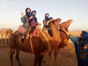 a group of people riding on the back of a camel at LA HACIENDA Agafay Desert 