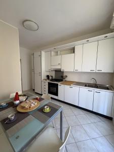 a kitchen with white cabinets and a glass table at Appartamento DIMORA GUIDI 3 camere 2 bagni URBINO in Urbino