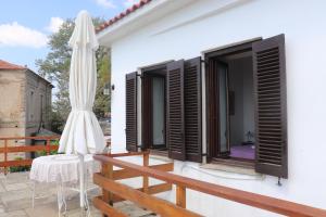 een wit huis met een parasol, een tafel en een terras bij Pelion country house in Volos