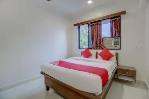 a bedroom with a bed with red pillows and a window at Hotel O Della Comforts in Ambernath