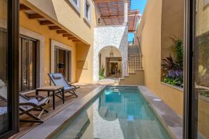 an indoor pool in a house with two chairs and a table at Designer Retreat in Centro Heated Pool & Views in San Miguel de Allende