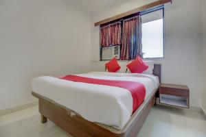 a bedroom with a bed with red pillows and a window at Hotel O Della Comforts in Ambernath