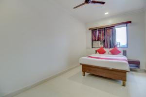 a bedroom with a bed with red pillows and a window at Hotel O Della Comforts in Ambernath +24 photos