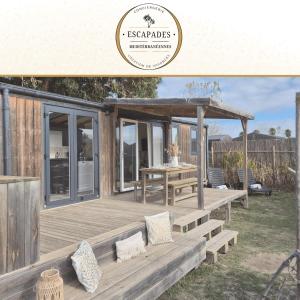 eine Holzterrasse mit einem Tisch und einem Pavillon in der Unterkunft Le Tropical Mobil Home à 200m de la plage Camping 5 Etoiles Parc Aquatique in Torreilles