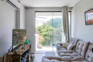 a living room with a couch and a large window at Calido 1BR Dpto, a minutos del Aeropuerto in Asuncion