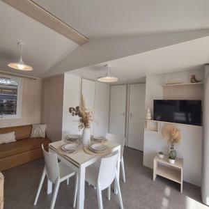 a living room with a table and white chairs at Le Tropical Mobil Home 6 Personnes - Plage à 200m - Parc Aquatique - Camping 5 Etoiles Les Dunes in Torreilles +30 photos