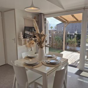 a white dining room table with white chairs and a white table and chairsktop at Le Tropical Mobil Home 6 Personnes - Plage à 200m - Parc Aquatique - Camping 5 Etoiles Les Dunes in Torreilles