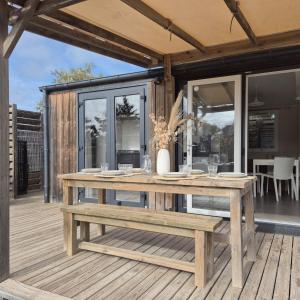 eine Holzterrasse mit einem Picknicktisch auf einem Haus in der Unterkunft Le Tropical Mobil Home à 200m de la plage Camping 5 Etoiles Parc Aquatique in Torreilles