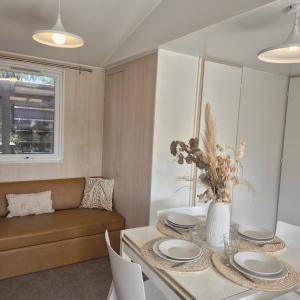 a dining room with a table and a couch at Le Tropical Mobil Home 6 Personnes - Plage à 200m - Parc Aquatique - Camping 5 Etoiles Les Dunes in Torreilles
