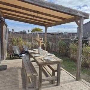 einem Holztisch und einer Bank auf einer Holzterrasse in der Unterkunft Le Tropical Mobil Home à 200m de la plage Camping 5 Etoiles Parc Aquatique in Torreilles