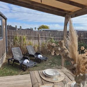 eine Terrasse mit zwei Stühlen und einem Tisch in der Unterkunft Le Tropical Mobil Home à 200m de la plage Camping 5 Etoiles Parc Aquatique in Torreilles + 17 Fotos