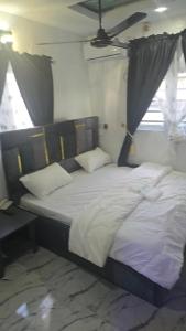 una habitación con una cama grande con sábanas y almohadas blancas en Hotel de mexico, en Warri