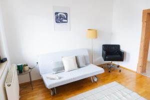 a living room with a white couch and a chair at raum life - Ferienwohnung Straubing #1 in Straubing