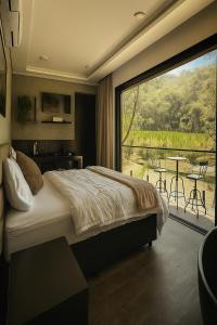 une chambre avec un grand lit et une grande fenêtre dans l'établissement Chalé com banheira, piscina e cachoeira privativa, à Taubaté