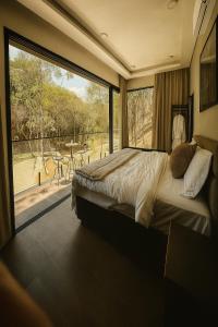 une chambre avec un lit et une grande fenêtre dans l'établissement Chalé com banheira, piscina e cachoeira privativa, à Taubaté