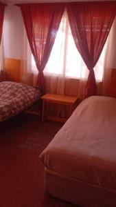 a bedroom with a bed and a window with curtains at Hostal Ribera de Quitor in San Pedro de Atacama