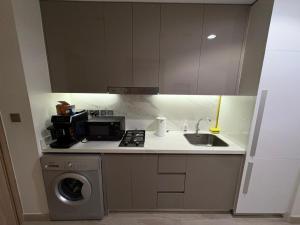 een keuken met een spoelbak en een wasmachine bij Deluxe studio water front in Dubai