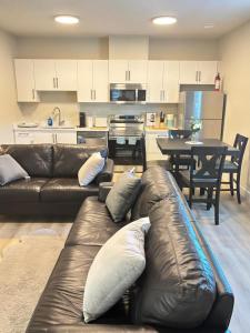 a living room with a leather couch and a kitchen at Prince George Cozy Suite in Prince George
