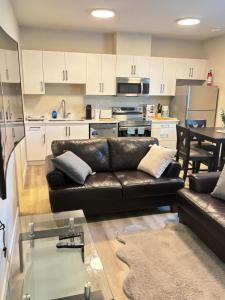 a living room with a leather couch and a kitchen at Prince George Cozy Suite in Prince George