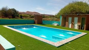 a swimming pool in a yard with green grass at Hostal Ribera de Quitor in San Pedro de Atacama +15 photos