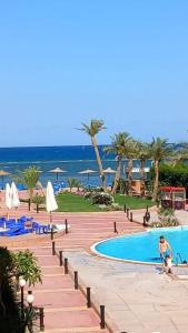 a person standing by a swimming pool at a resort at cecelia resort in Hurghada