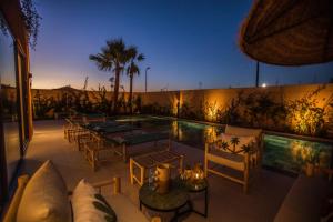 a patio with chairs and a swimming pool at night at Villa Marleanis 5 suites 300m2 piscine chauffée privative 11m de long résidence avec gardien in Marrakesh