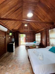a bedroom with two beds and a wooden ceiling at Cabañas Bacali in Bacalar