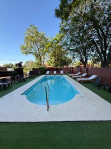 Una piscina en un patio con mesas y sillas. en Terra Iguazú Suites, en Puerto Iguazú