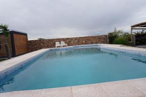 a large blue swimming pool with two chairs in it at Cabañas La Sarita in La Consulta
