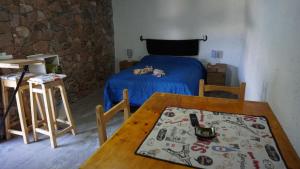 a bedroom with a table and a bed with a blue blanket at Cabañas La Sarita in La Consulta +22 photos