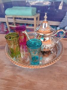 a tray with four different colored glasses and a tea pot at LA HACIENDA Agafay Desert 